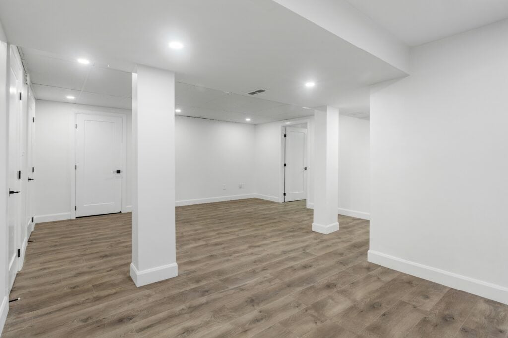 Finished basement with white walls, recessed lighting, and wood-look vinyl flooring