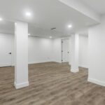 Finished basement with white walls, recessed lighting, and wood-look vinyl flooring