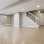 DIY Basement Floor Epoxy Coating for Concrete Floors Finished basement with glossy epoxy floor coating and gray walls under recessed lighting