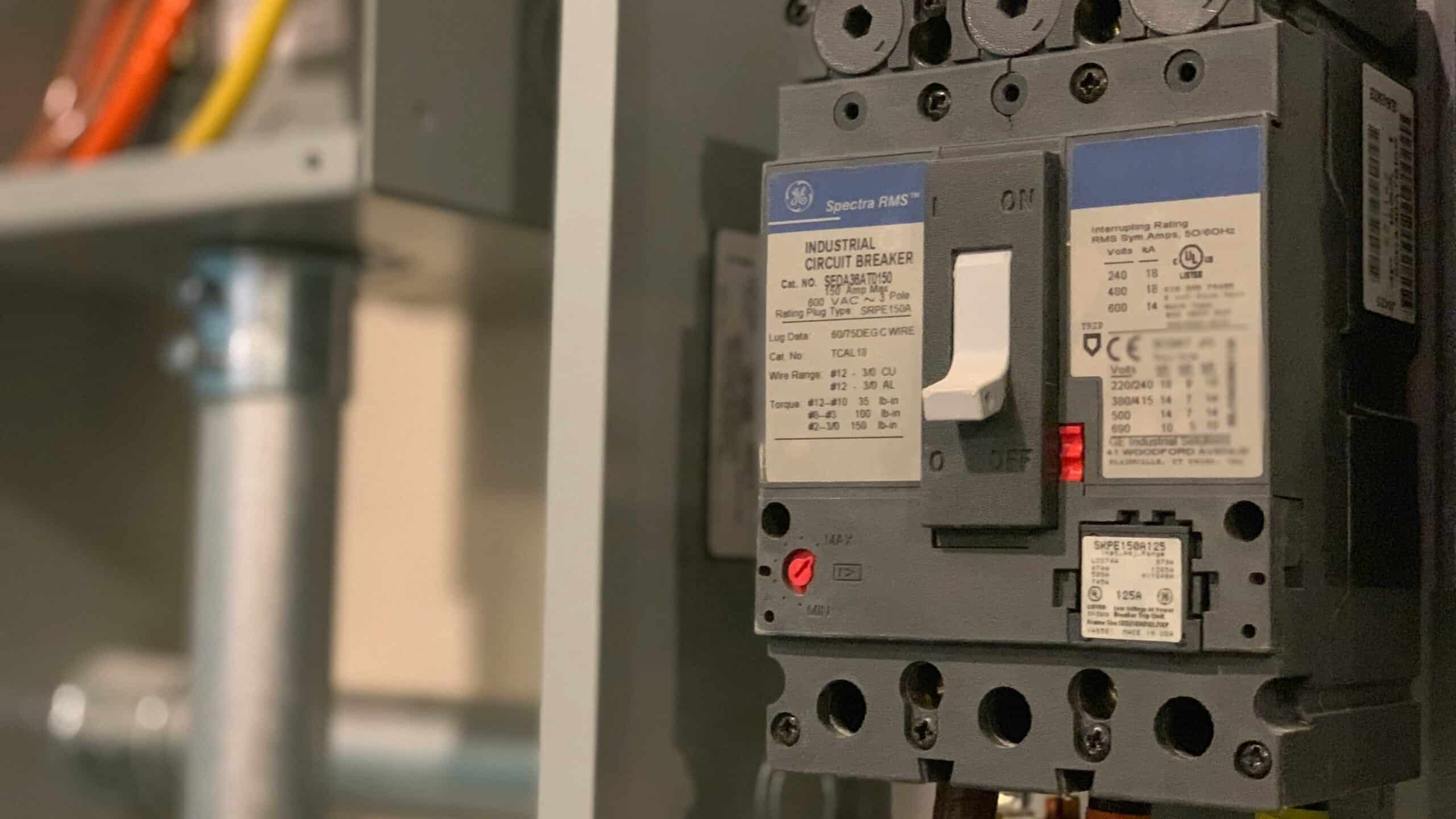 Industrial-grade home electrical circuit breaker with labeled wires and conduit inside a residential panel box