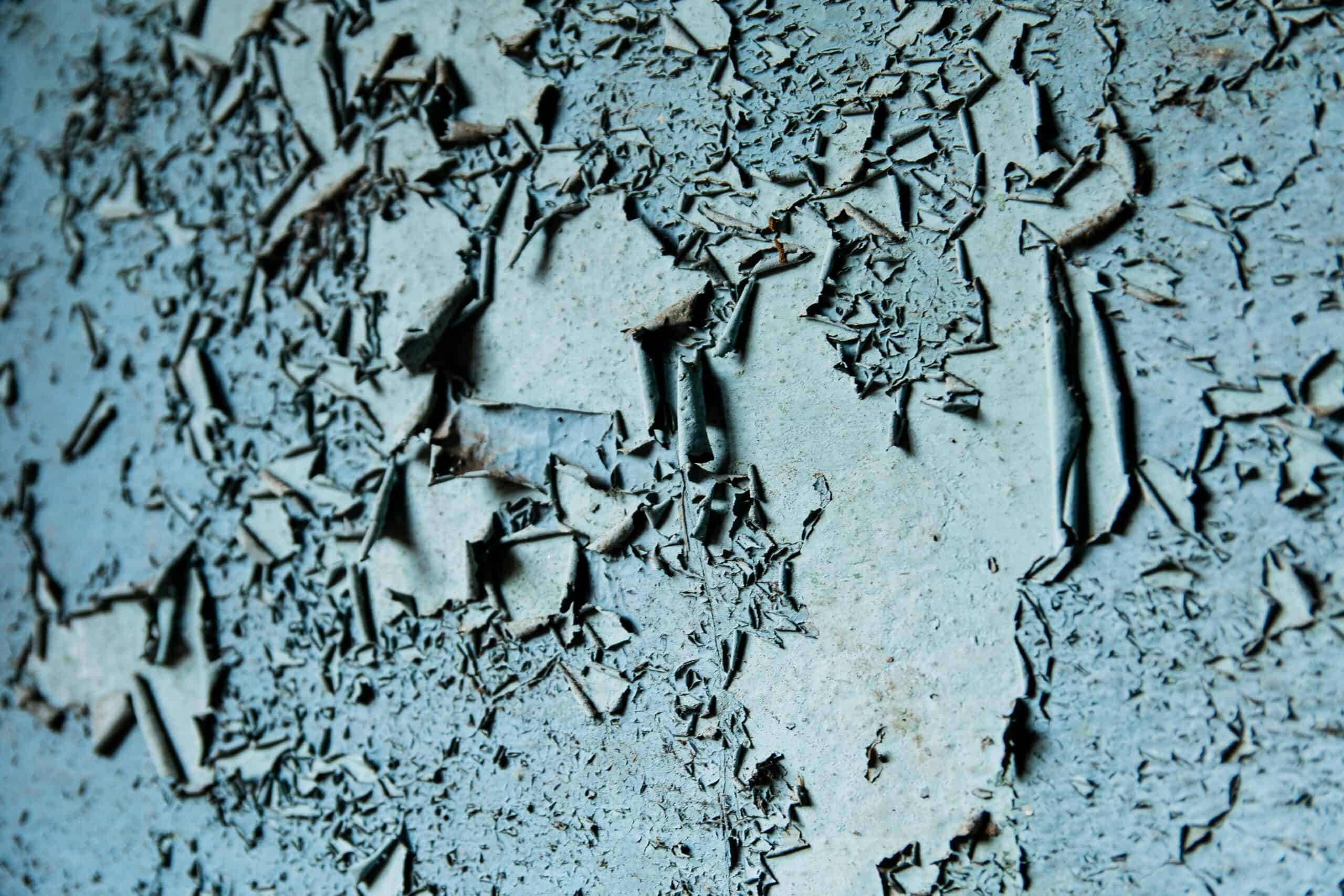 Peeling paint and bubbling drywall on a damp basement wall showing early signs of moisture damage and waterproofing failure
