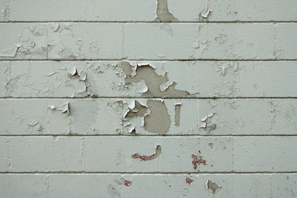 Peeling paint on a concrete basement wall caused by moisture and vapor pressure