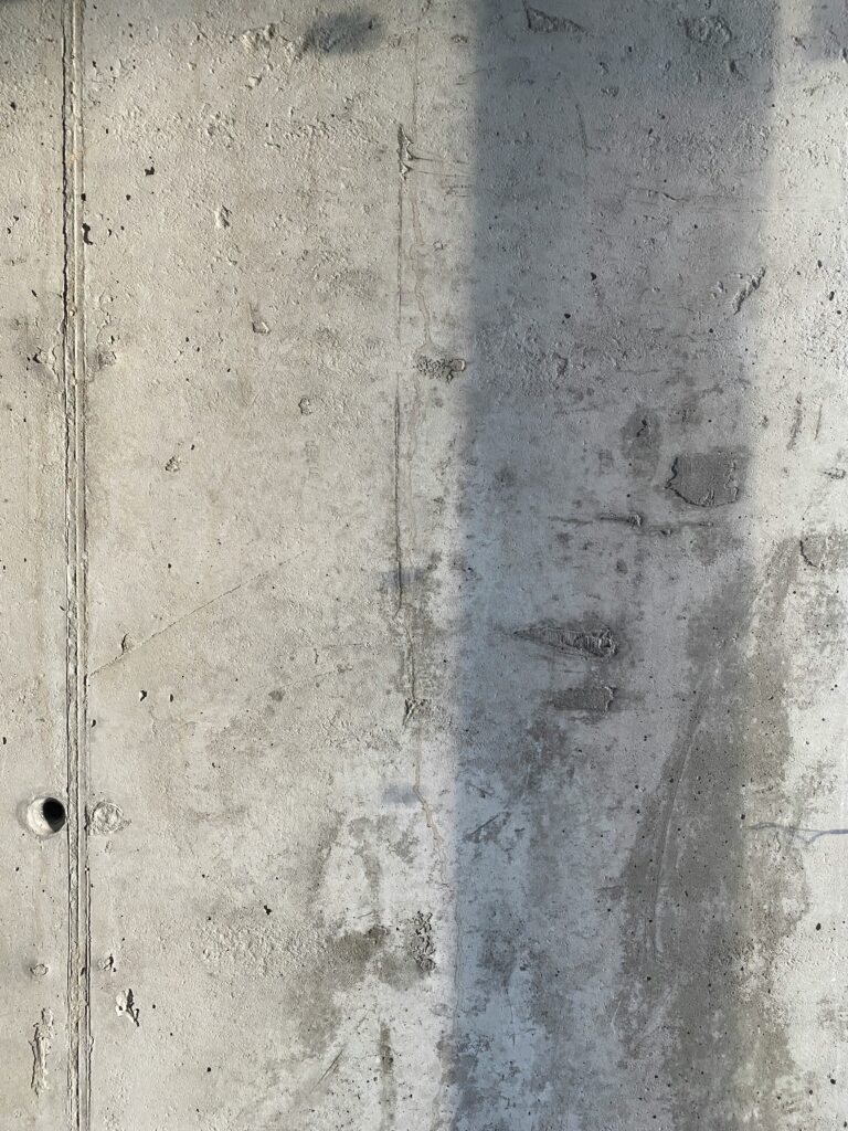 Damp concrete basement wall showing moisture staining and discoloration, indicating walls are not ready for painting