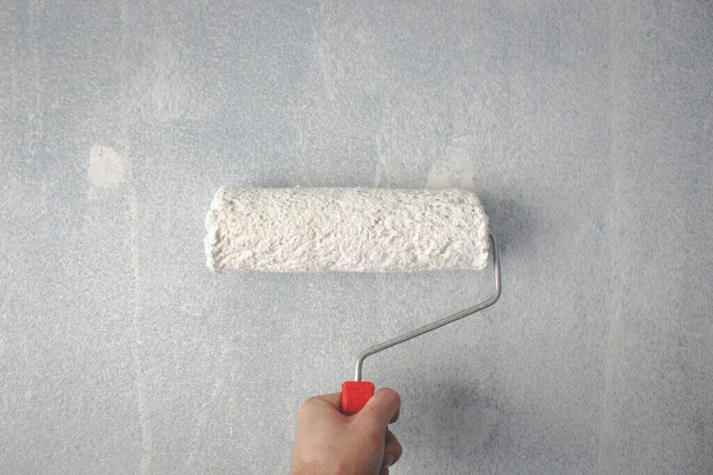 Painting basement walls with a roller using waterproof paint on concrete surface