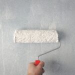 Painting basement walls with a roller using waterproof paint on concrete surface