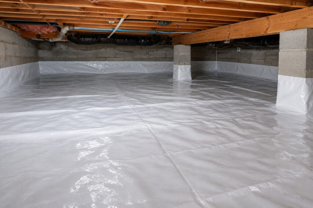Clean crawl space with white vapor barrier installed over the floor and foundation walls to help control moisture.