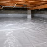 Clean crawl space with white vapor barrier installed over the floor and foundation walls to help control moisture.